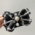 Detail of plaid fabric bow hair clip featuring an elegant large pearl center and pendant - Black