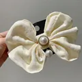 Detail of cream plaid bow hair clip with large faux pearl and sparkling rhinestone center - Off White