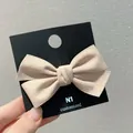 Vue détaillée d'une barrette à nœud en suédine beige sur une carte noire - Abricot