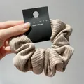 Detail shot of apricot knitted striped scrunchie with elastic pleats and black label - Khaki Large