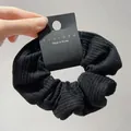 Detail of black striped knit fabric hair scrunchie with brand tag and soft texture - Black Large