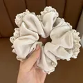 Detail of beige velvet scrunchie with delicate lace edges and gold metal tag - Off White