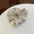 Detail of checkered and satin fabric patchwork scrunchie with soft beige tones - Beige - Patchwork Hair Tie