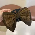 Bruine haarstrik met wafelstructuur stof stiksels op een merk kaartje - Haarclip