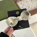Primer plano de un pasador de pelo con lazo crema de cuero sintético en una tarjeta - Albaricoque