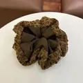 Detail van een koffiebruine scrunchie met een mix van satijn en pluche geruite texturen - Haarelastiek A