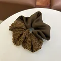 Detail van een donkerbruine scrunchie met een mix van matte zijde en getextureerde fleece - Haarelastiek B