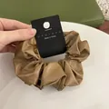 Detail of brown faux leather scrunchie with Nyu Nyu branding tag and premium texture - Camel