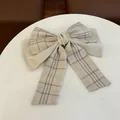 Details der karierten Schleifen-Haarspange mit Perlenbesatz und goldenem Emblem - Beige Perle Schleife Band Haarspange