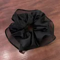 Detail of large black satin scrunchie with sheer mesh trim on a dark wooden background - Black