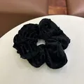 Macro-opname van zwarte fluwelen scrunchie met subtiele lovertjes en textuurplooien - Effen Kleur Scrunchie - Zwart