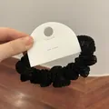 Detail van een geplooide zwarte scrunchie met zijdeachtige textuur en Koreaanse verpakking - Zwart