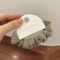 Detalle de coletero metálico oro champán con textura plisada en tarjeta de venta - Gris Albaricoque
