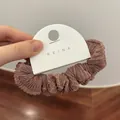 Detalle de coletero plisado en oro rosa metálico que muestra textura de seda detallada - Rosa Palo