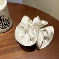 Elegant oversized cream white satin scrunchie with layered ruffles on wooden surface - Creamy Apricot