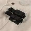 Primer plano de dos horquillas con lazo de satén negro sobre tarjeta en fondo de lino - Negro