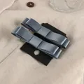 Detalle de horquillas con lazo de satén azul grisáceo sobre fondo de lino natural - Azul