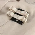 Vista macro de dos elegantes pinzas para el cabello con lazo de satén crema en tarjeta - Blanco Roto