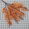 Vibrant orange artificial willow branches with detailed leaf veins on checkered background - Orange