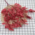 Artificial red peanut leaf branch with berries on a rustic woven mat background - Red