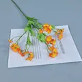 Künstliche Kamillenzweige mit leuchtend orangegelben Seidenblütenköpfen im Detail - Orangerot