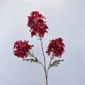 Three-headed deep red artificial hydrangea with long green stems on grey fabric background - Red