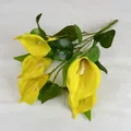 Vibrant yellow PU calla lily bouquet with detailed green leaves on white fabric background - Yellow