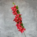 Artificial red bougainvillea branch with green leaves on grey concrete background - Red
