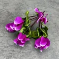 Vibrant purple artificial cyclamen silk flowers with variegated green foliage on grey - Purple