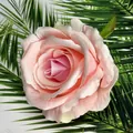 Pink and cream faux rose flower head with green leaf on palm background - Pink