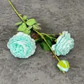 Lichtblauwe kunstmatige 3-koppige roos met twee bloemen en een knop op donkere stof - Blauw
