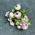 Pink and purple faux ranunculus bouquet with green leaves on grey fabric background - Purple