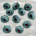 Flat lay of 10 blue-grey silk camellia flower heads for DIY headwear and crafts - Haze Blue
