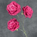 Trois roses artificielles en soie rose foncé avec tiges vertes sur fond gris foncé - Rouge Rose