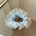 Detailansicht hellblauer Satin-Haargummi mit Schichten aus weißer Organza-Netzspitze - Blau