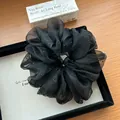Nahaufnahme von schwarzem Organza-Haargummi mit Perlenverzierung und feiner Textur - Schwarzes Zirkonia-Haargummi