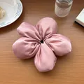 Dettaglio di un elastico per capelli a fiore in raso rosa lucido su tavolo in legno - Rosa