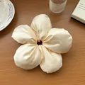 Détail d'un chouchou fleur en satin crème sur une table en bois aux tons chauds - Poche zippée