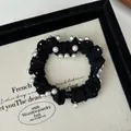Detail shot of a black fabric scrunchie with elegant white pearl accents on jewelry tray - Black