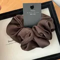 Close-up of coffee brown silk scrunchie with brand tag on a premium display tray - Dark Coffee