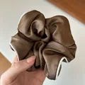 Gros plan sur un chouchou en satin marron café avec une bordure blanche contrastée - Café Clair