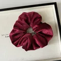 Dettaglio dell'elastico scrunchie in velluto rosso vino con glitter metallici e pieghe - rosso Angola