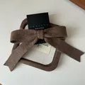 Nahaufnahme einer dunkelbraunen gestrickten Schleifenspange auf einem Holztablett - Braun
