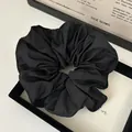 Detail view of a black ruffled scrunchie featuring elegant wavy edge stitching craftsmanship - Black