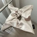 Detailed macro view of handmade champagne satin silk scrunchie with gloss texture - Beige Apricot