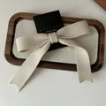 Gestrickte Schleifen-Haarspange in Cremeweiß mit Rippenstruktur auf Displaykarte - Aprikose