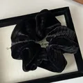 Detail of black velvet scrunchie with ribbed texture on a minimalist display - Black
