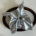 Macro view of silky silver-grey satin scrunchie with a Hand Made woven label on wood - Grey Blue