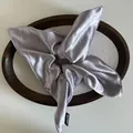 Detailed view of lavender satin scrunchie with Hand Made label on a wooden tray - Light Purple