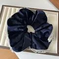 Detailopname van donkerblauwe fluwelen scrunchie met witte kant op een dienblad - Marineblauw